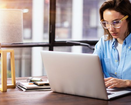 Woman working with a laptop with lamp on desk